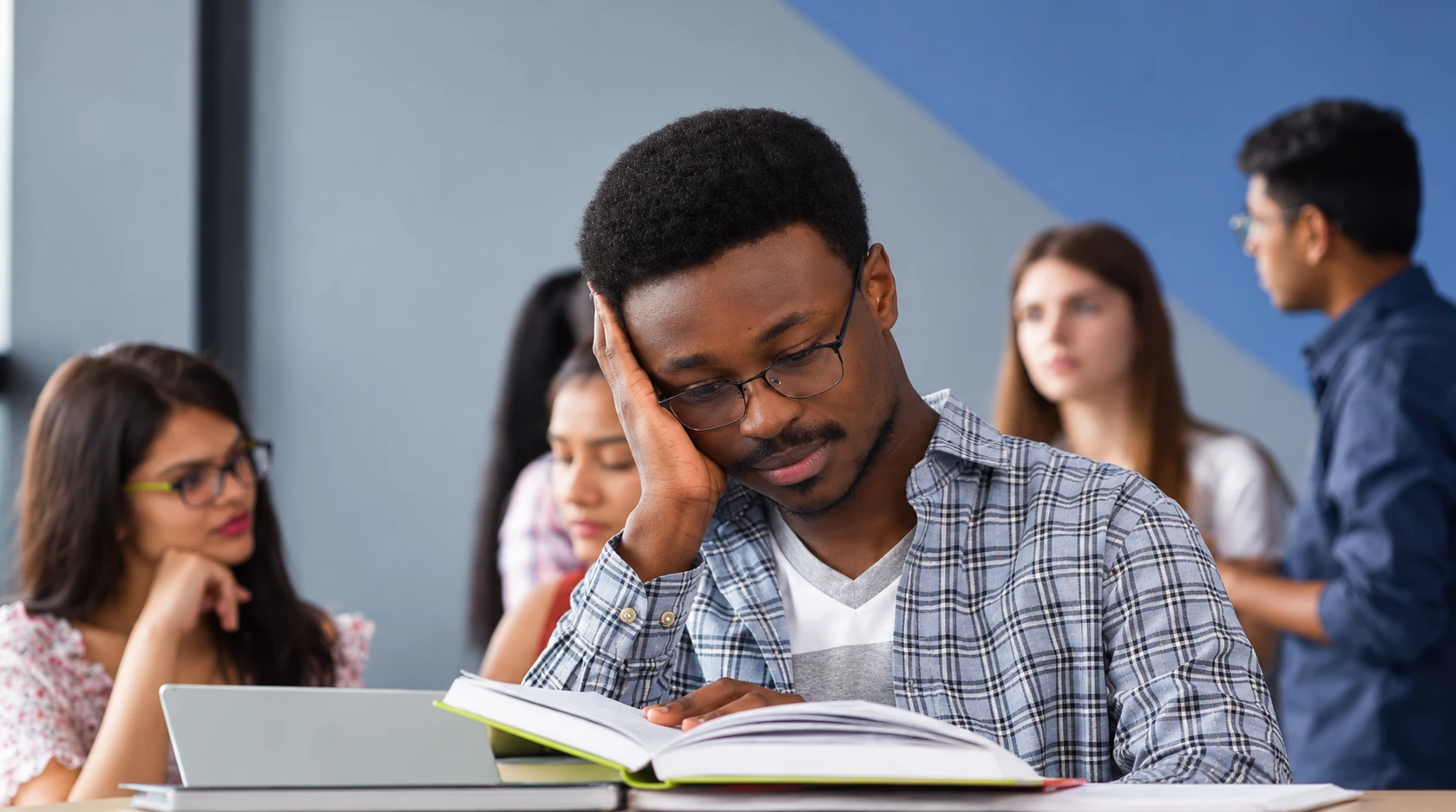 A student reading an open textbook in a classroom